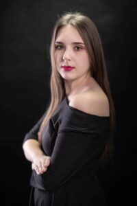 Anna Zborowska w czarnej sukience, ciemne tło