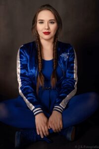 Anna Zborowska z warkoczami, siedząca, ciemne tło