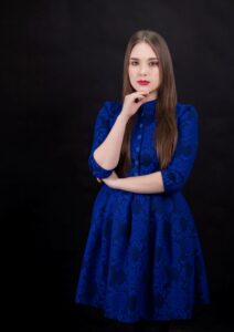 Anna Zborowska w kobaltowej sukience, ciemne tło