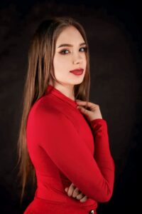 Anna Zborowska w czerwonej bluzce, ciemne tło