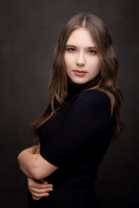 Anna Zborowska w czarnej bluzce, portret do pasa, ciemne tło