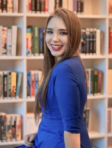 Anna Zborowska przy regale z książkami w bibliotece