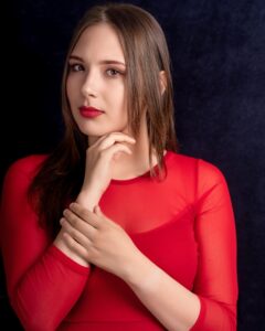 Anna Zborowska w czerwonej bluzce, ciemne tło