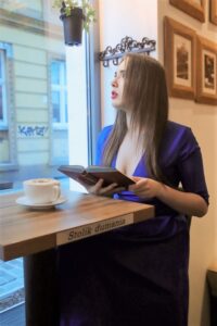 Anna Zborowska z książką i kawą przy oknie