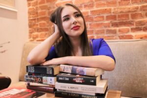 Anna Zborowska oparta o stos książek w kawiarni