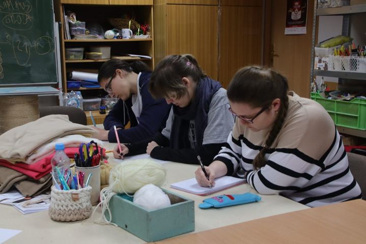 Uczestniczki warsztatów piszą w zeszytach