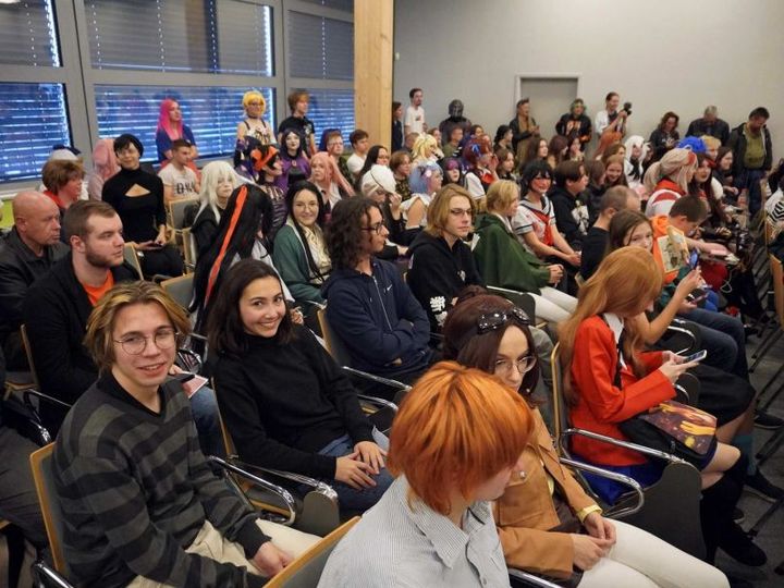 Pełna sala publiczności, część osób w kolorowych przebraniach, podczas spotkania z autorką